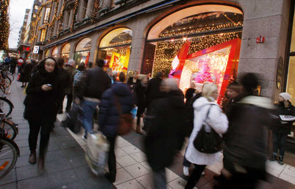 People walk past Christmas window displays at a department store in Stockholm.