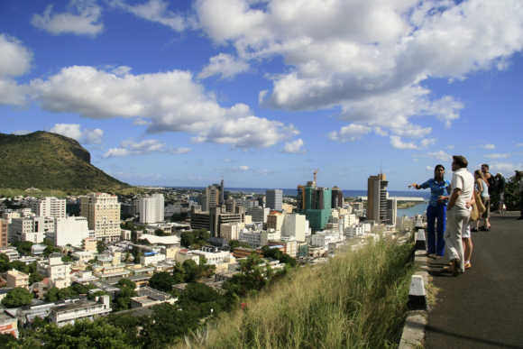 A tour guide stands with a group of tourists at a viewpoint overlooking Port Louis.