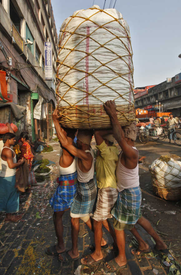 Workers carry a packed basket of vegetables at a wholesale market in Kolkata.