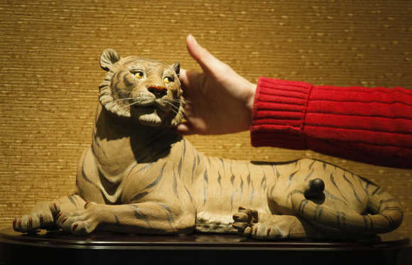 Worker introduces a ceramic tiger to visitors at an exhibition hall of Xinshiwan ceramic factory in Foshan, Guangdong province, China.