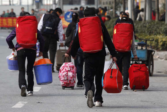 Migrant workers carrying their luggage walk to the Dongguan East train station in China