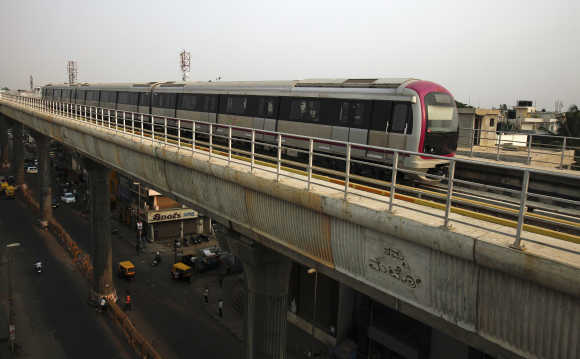 Metro train travels along an elevated track as traffic passes below in the Indira Nagar area of Bangalore.