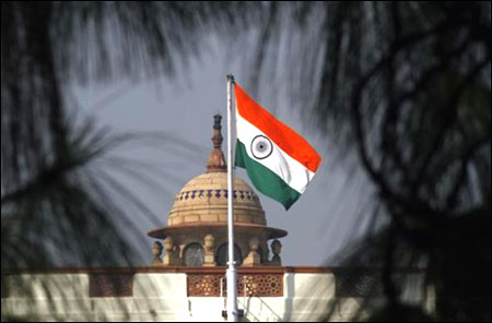 An Indian national flag flutters on top of the parliament building.
