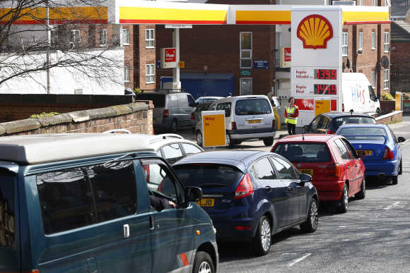 A worker monitors the queue as motorists wait for fuel at a filling station in Liverpool.