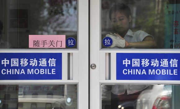A worker cleans the door of a China Mobile branch in Shenyang, China.