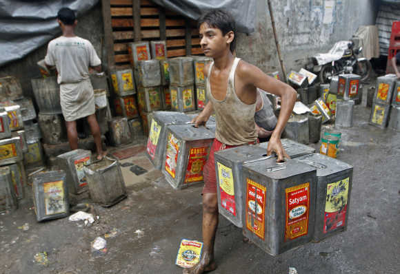 A boy carries recycled mustard oil tin containers from a roadside workshop in Kolkata.
