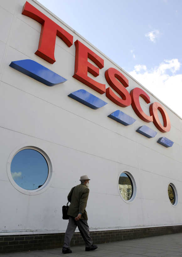 Man passes a branch of the Tesco supermarket in central London.