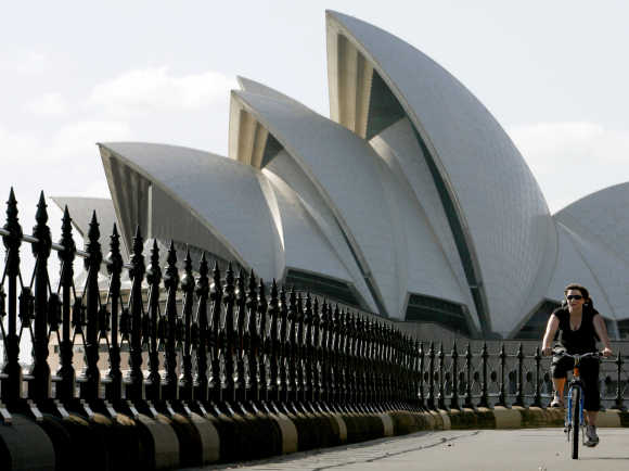 A cyclist rides past the Sydney Opera House in Australia.