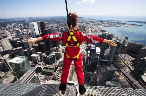 A reporter leans over the edge during the media preview for the 'EdgeWalk' on the CN Tower in Toronto.