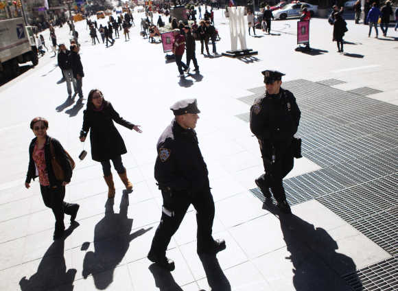 Two police officers walk amongst passing tourists in Times Square during a warm winter day in New York.