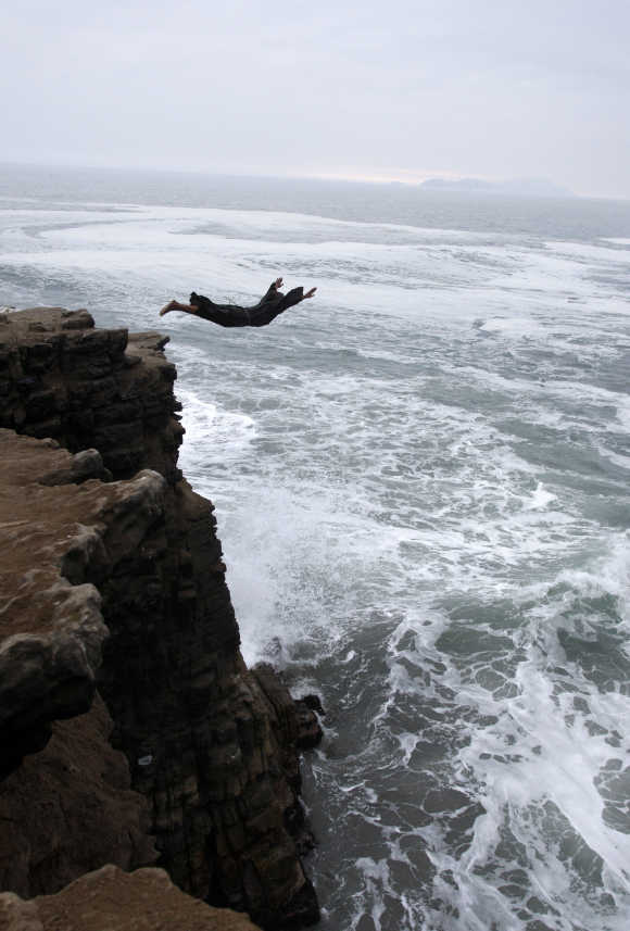 A man dressed as a friar jumps from a 10 metre (33ft) cliff in Lima, Peru.