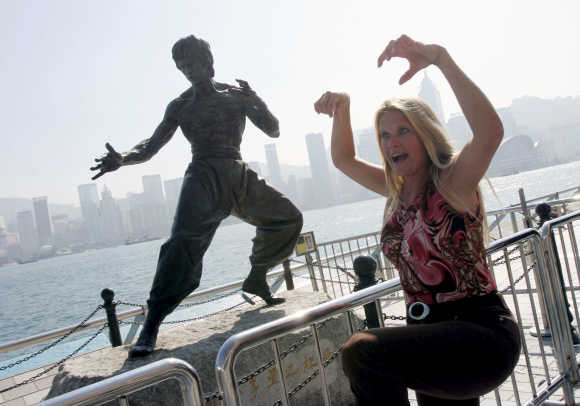 A tourist poses in front of a statue of Bruce Lee on the Avenue of Stars along the Tsim Sha Tsui waterfront in Hong Kong.