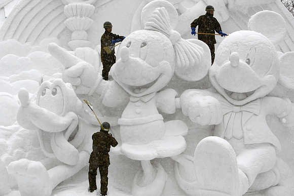 Soldiers clear snow on a sculpture at a festival in Sapporo.