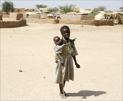 A refugee girl from Darfur carries her brother outside the International Medical Corps' clinic at Mile refugee camp in eastern Chad.