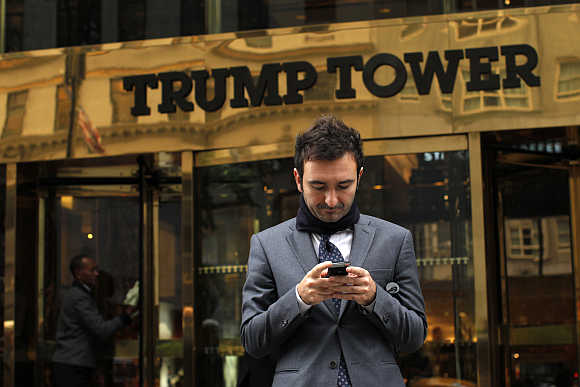 A man types on his mobile phone in front of the Trump Tower in New York.