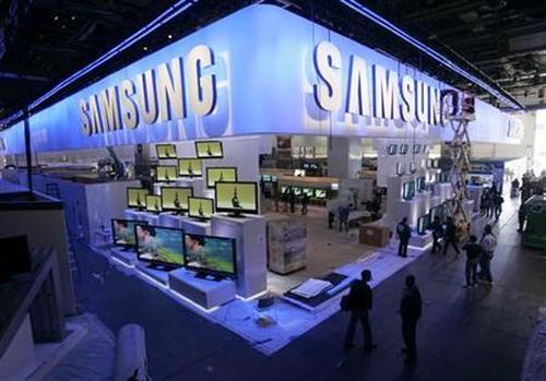 A worker cleans the sign hanging over the Samsung booth