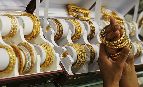 A customer tries gold bangles inside a jewellery showroom in Noida.