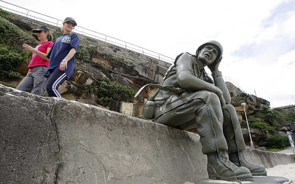 Two women walk past a work by artists Bellotti and Rosewell, which is part of 'Sculpture by the Sea', near Bondi Beach.
