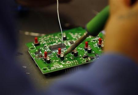 A worker solders a circuit board