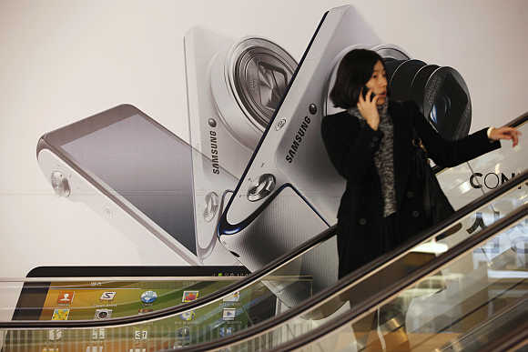 A woman talks on her phone in front of an advertisement promoting Samsung Electronics' Galaxy Camera in Seoul.