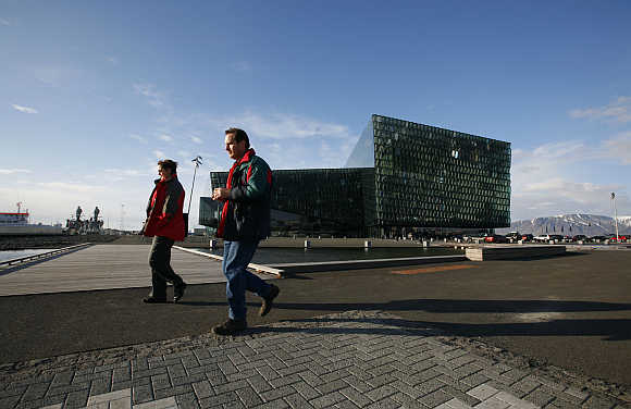 People walk past the Harpa Concert Hall in downtown Reykjavik.
