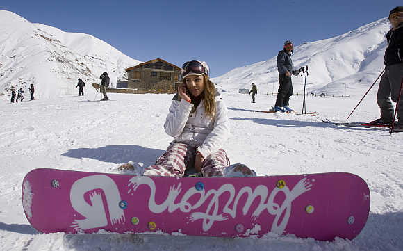 A woman speaks on her mobile phone at the midway point of a slope at Shemshak ski resort.