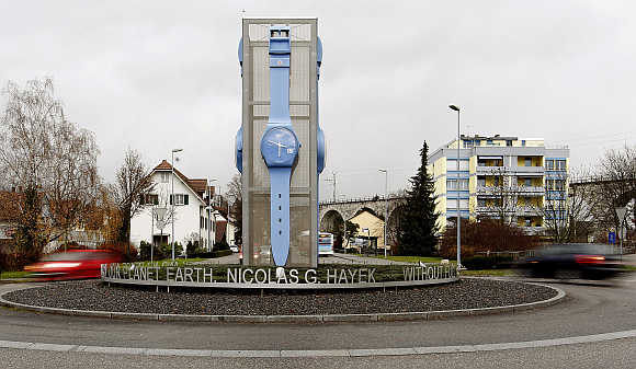 Cars drive past a giant Swatch watch placed in the centre of a roundabout in Swiss town of Grenchen.