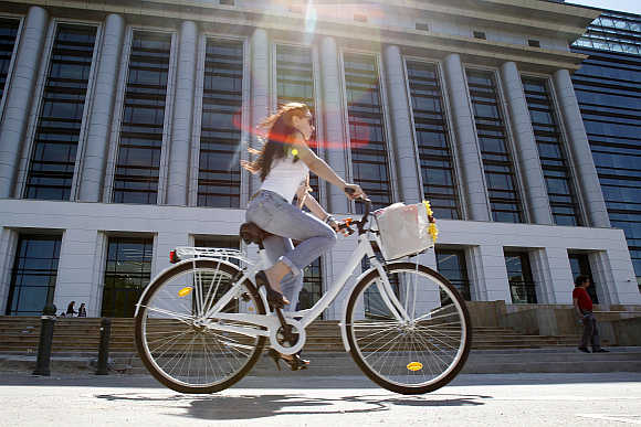 A woman rides her bicycle past Romania's National Library in Bucharest.