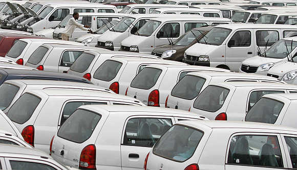 A worker adjusts the windscreen wipers of a parked car at a Maruti Suzuki stockyard on the outskirts of Ahmedabad.