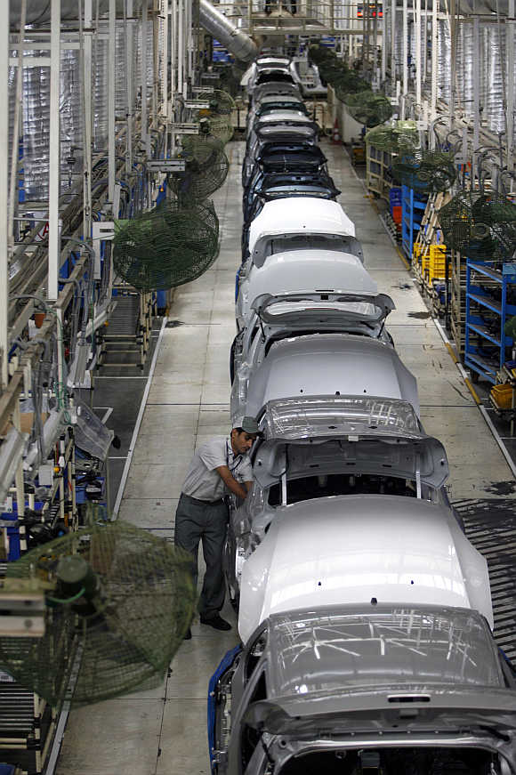 A worker inspects a car at a Maruti Suzuki plant in Manesar.