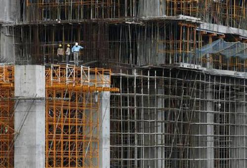 Workers stand at a construction site of a high rise building.