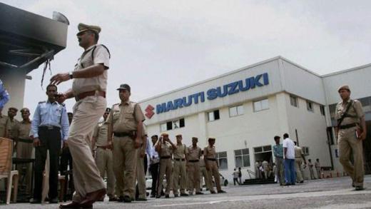 Police officials walk outside the Maruti Suzuki's plant in Manesar