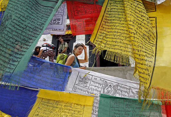 French tourist walks past Buddhist religious flags at Namgyal Tsemo Gompa monastery in Leh.