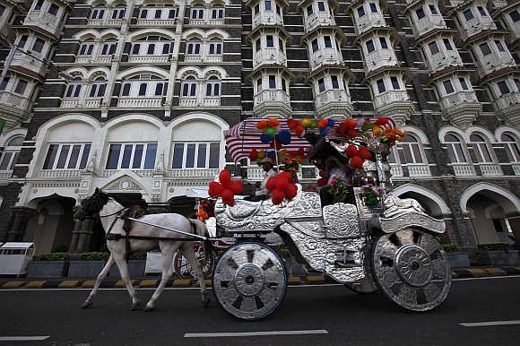 A horse-drawn carriage carrying tourists moves past the Taj Mahal hotel in Mumbai.