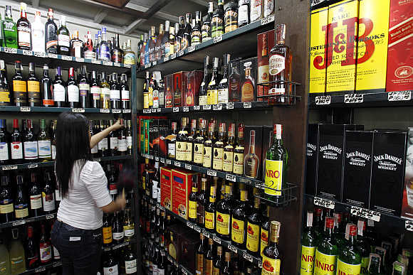 A saleslady cleans a display inside a wine shop in Manila, Philippines.