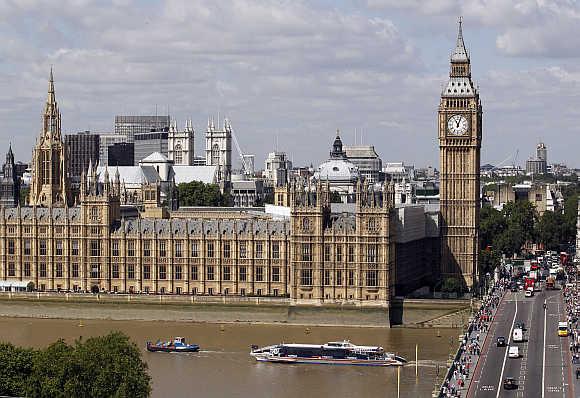 Traffic on the road and the Thames passes the Houses of Parliament in London.