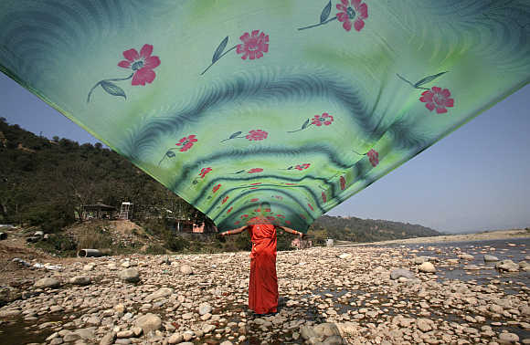 A woman dries her saree after washing it on the banks of river Tawi in Jammu.