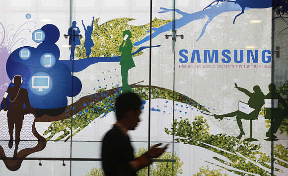 A man using a mobile phone walks past a Samsung Electronics' advertisement in Seoul.