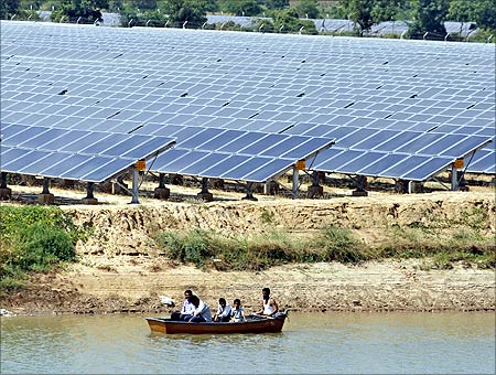 Security personnel sit in a boat as they patrol the premises of a newly inaugurated solar farm at Gunthawada village in Banaskantha district.