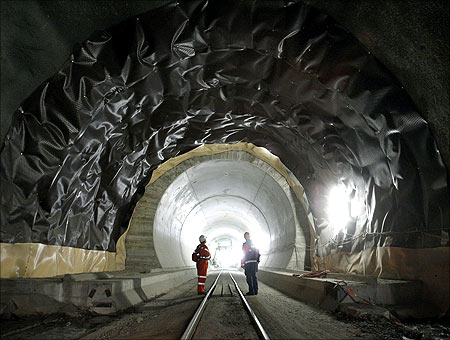 A worker and a visitor stand at the construction site of the NEAT Gotthard Base Tunnel at the Erstfeld-Amsteg section.