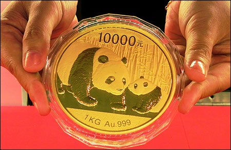 An employee shows a golden panda ingot at a gold store in Hangzhou, Zhejiang Province of China.