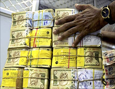 A bank employee counts bundles of Indian currency at a cash counter in Agartala.