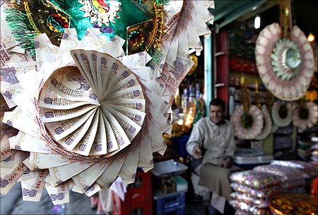 A Kashmiri shopkeeper sits near garlands made of Indian currency notes at a market in Srinagar.