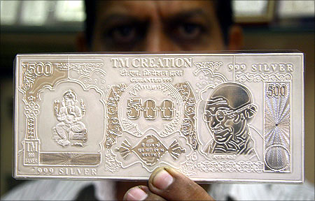  A jeweller displays a silver plate in the form of an Indian rupee note.