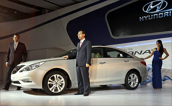 Arvind Saxena (L), director for sales and marketing at Hyundai India, Park Han Woo (C), managing director of Hyundai India, and a model pose with the company's new Sonata car after its launch at India's Auto Expo in New Delhi.