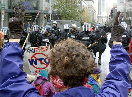 A woman raises her hands in a peace sign as riot police take back control of a downtown intersection in Seattle.