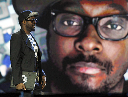 Recording artist Will.i.am walks past an oversized image of himself as he arrives on stage during an Intel keynote address at the 2012 International Consumer Electronics Show.