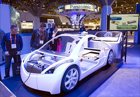 Visitors check a display at the Panasonic booth showing electric vehicle technology.