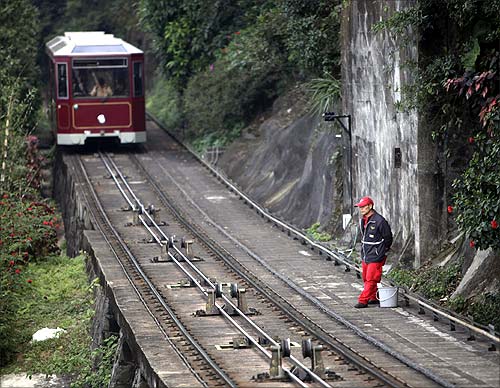 A worker stands next to a track as a tram approaches on its way up The Peak in Hong Kong.