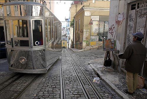A street artist looks at a Bica funicular tram.